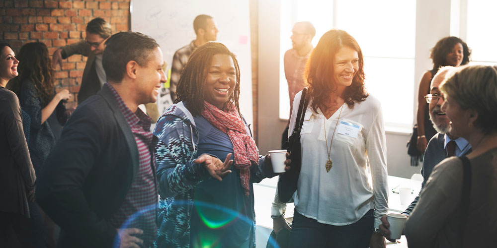 A diverse group of professionals gathered in an office, engaged in discussion and collaboration.