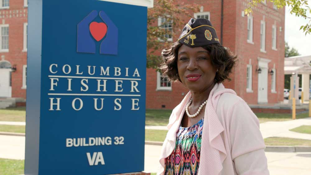 Woman in military hat in front of fisher house